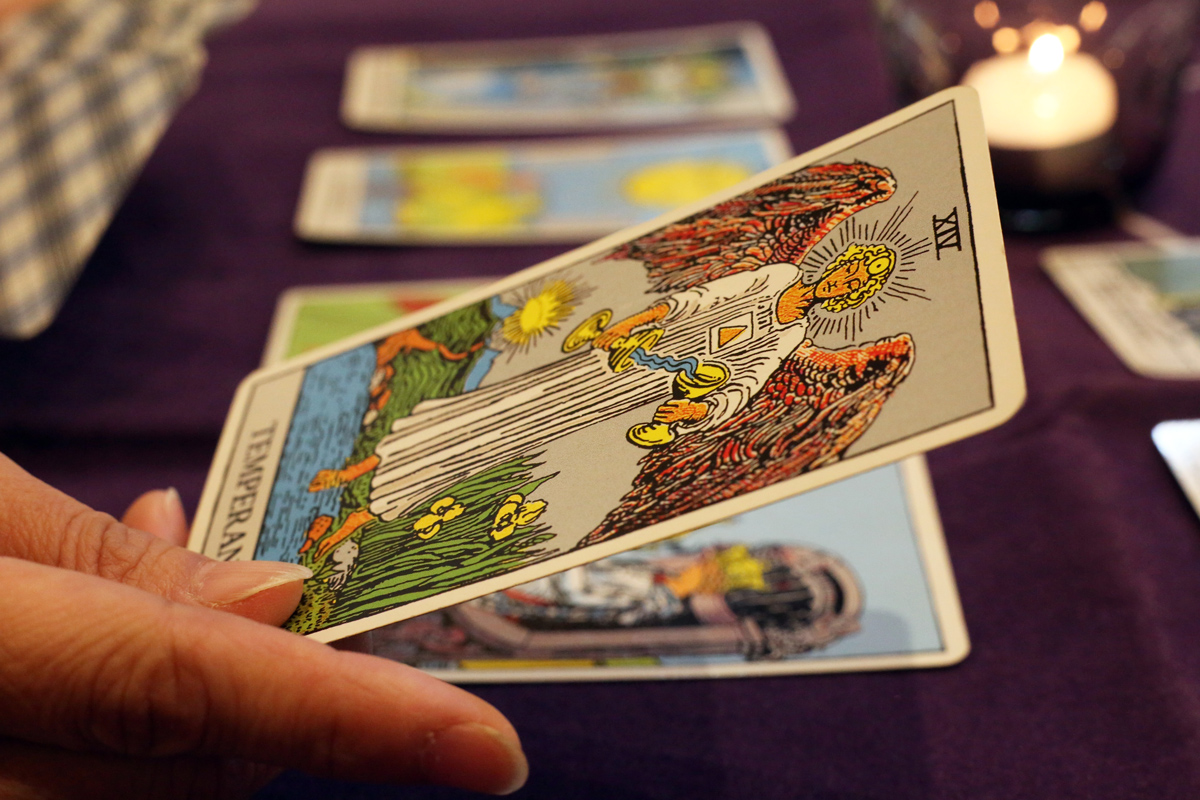 A Tarot Card featuring and angel with wings. Other Tarot Cards lay on the table for the reading.